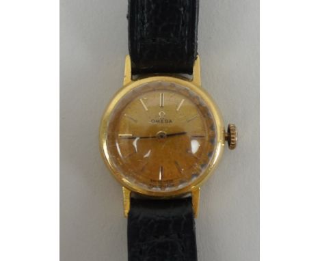 An 18ct gold cased lady's Omega wristwatch, with circular gold coloured face and index batons, black stick hands, black third