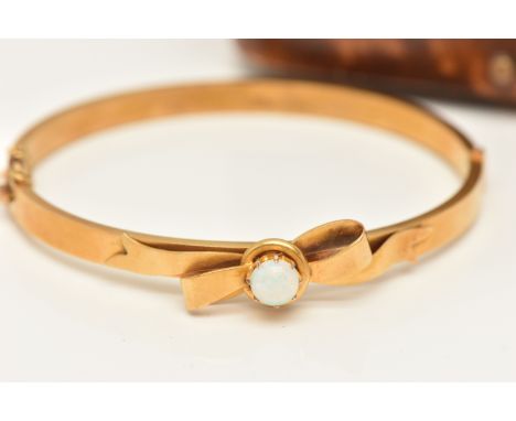 A 15CT GOLD OPAL HINGED BANGLE, a yellow gold hollow bangle with bow detail and a centrally set round opal, fitted with an in