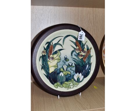 A FRAMED 'LAMIA' MOORCROFT CHARGER depicting water lilies and bulrushes, designed by Rachel Bishop, mounted in a circular fra