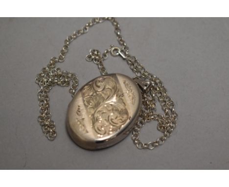 A silver locket of oval form having engraved scroll decoration and silver belcher chain, approx 21.6g