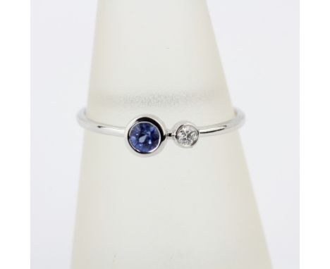 An 18ct white gold ring set with a round cut sapphire and a brilliant cut diamond, ring size N.