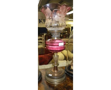 A Victorian oil lamp with brass base, cranberry glass reservoir and original cranberry frosted shade 