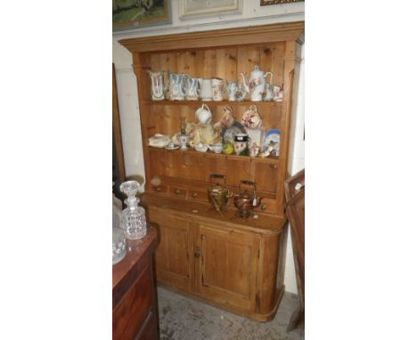 A traditional pine dresser with shelf top, small drawers below and twin cupboard doors beneath