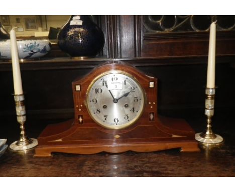 A mahogany and mother-of-pearl inlaid mantel clock and a pair of similar candlesticks