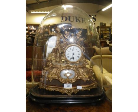 A Victorian spelter mantel clock decorated with a male figure in period costume, on a giltwood base under a glass dome on ebo