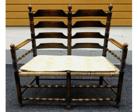 A TWO-SEATER OAK FRAMED RUSH SEATED LADDER BACK SETTEE Provenance: Estate of Helen Zienkiewicz Deceased (1926-2016) late wife