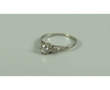 AN ANTIQUE DIAMOND RING with round cut diamond & small diamonds to the shoulders set in white metal