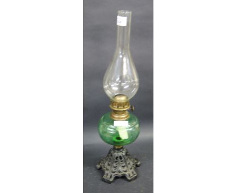 An oil lamp of traditional form with a cast iron base, coloured glass reservoir and clear chimney