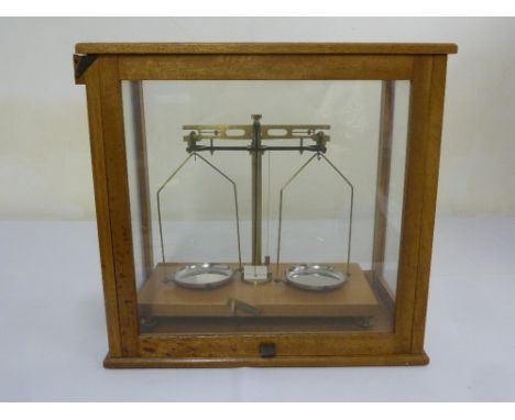 A 20th century balance scales of customary form in a wood and glazed case