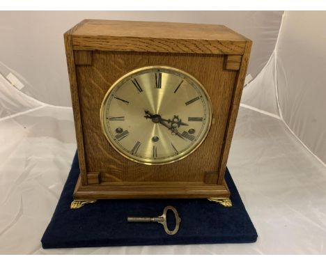AN OAK CASED BRAVINGTONS LTD (RENOWN SUPER) EIGHT DAY MANTEL CLOCK WITH BRASS CLAW FEET AND KEY 