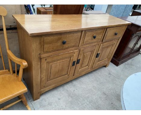 A MODERN LIGHT OAK ANTIQUE STYLE SIDEBOARD ENCLOSING THREE DRAWERS AND THREE CUPBOARDS, 66.5" WIDE 