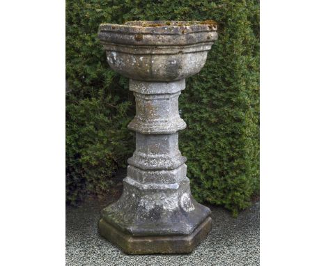 A carved limestone font, 17th century, of hexagonal form, the basin above a knopped and finned pillar and spread base, 92cm h