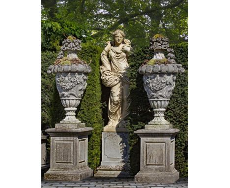 A pair of monumental carved limestone urns-and-covers, in Louis XVI taste, 20th century, each with a basket-of-fruit finial a