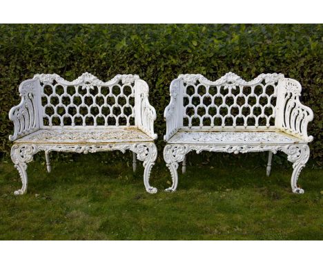 A pair of white painted cast iron garden seats, late 19th century, each with arcaded back beneath a scrolled top rail, the og