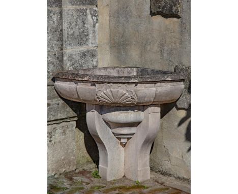 A French limestone corner wall fountain basin, 19th century, the front centred by a stylised scallop-shell carved in low reli