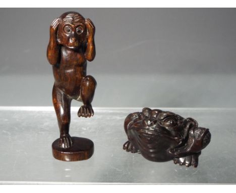 Netsuke - two Japanese Netsukes one depicting a monkey standing on one leg the other depicting a frog or toad, both signed an