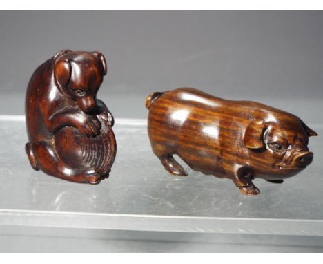 Netsuke - two vintage dark wood Japanese Netsukes one depicting a dog holding a shell between its legs and the other is depic