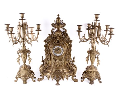 A 20th Century German rococo style brass mantel clock garniture. Striking to two bells, brass dial, white enamel Roman numera