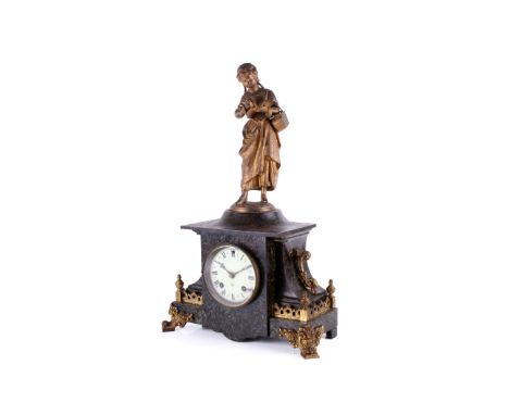 A Victorian slate mantel clock. Surmounted by a gilt metal figure reading a book. An Ansonia eight day movement, striking to 
