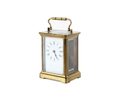An Edwardian Brass carriage clock. With a porcelain face, brass handle above a visible escapement, bevelled edge glass to gla