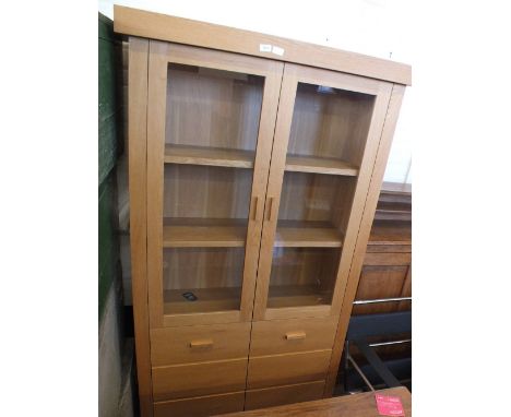 A modern light oak glazed display cabinet with faux drawers