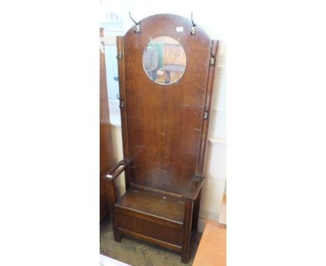 An oak hall stand with circular mirror, flanked by stick stands with trays