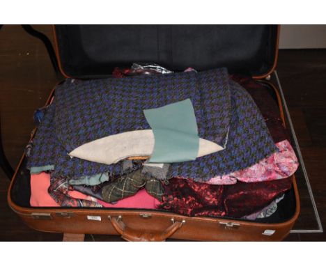 A suitcase containing vintage and retro clothing alongside and unfinished Welsh wool style cape.