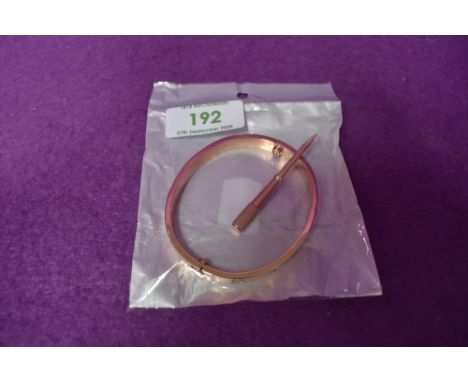 A Rose gold coloured copy love bangle bearing the name Cartier  with screw driver