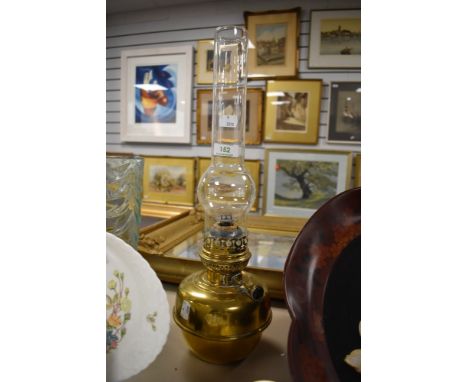 An antique brass desk top oil lamp with glass chimney.