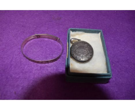 An HM silver locket of oval form having engraved foliate decoration and a white metal christening bangle stamped sterling sil
