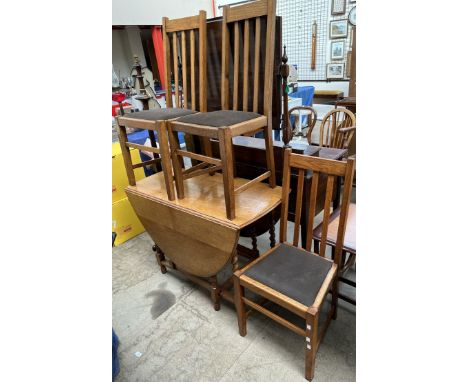 An oak gateleg dining table together with a set of four oak dining chairs and a standard lamp