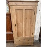 A continental pine wardrobe with a moulded cornice above a single door and two base drawers on