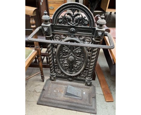 A cast iron stick stand, decorated with flowers and leaves
