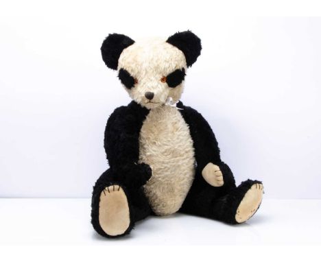 with black and white mohair, orange and black plastic eyes, black stitched nose, mouth and claws, swivel head and jointed lim