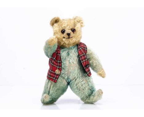 with blonde mohair head and hand pads, orange and black glass eyes, black stitched nose, blue mohair body with jointed arms a