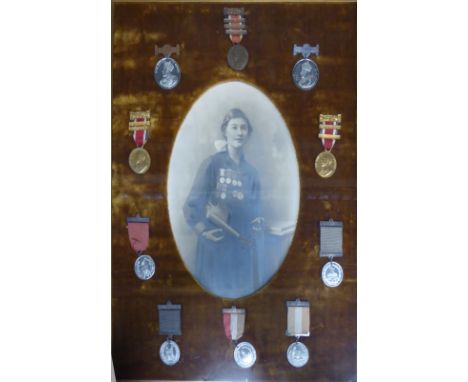 An early 20th century oval Photographic Portrait of M Samways holding a violin, the surround set with her various medals and 