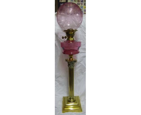 A brass Corinthian column Table Oil Lamp with cranberry glass reservoir and etched shade, on a stepped square base, 2' 9" (84