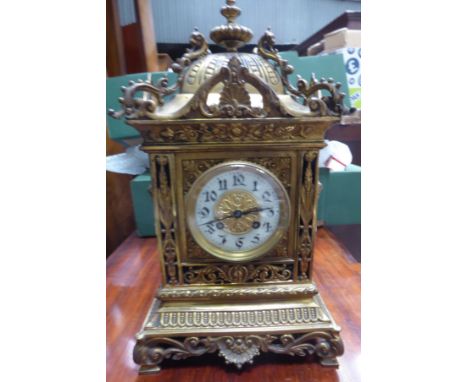 An early 20th century Mantle Clock with white dial and striking movement, in a brass case, with urn finial, decorated with ma