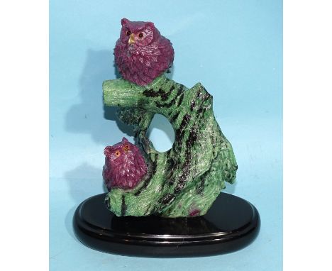 A ruby and zoisite crystal carving of two sitting ruby baby owls perched on the integrated zoisite tree trunk base, the owls 