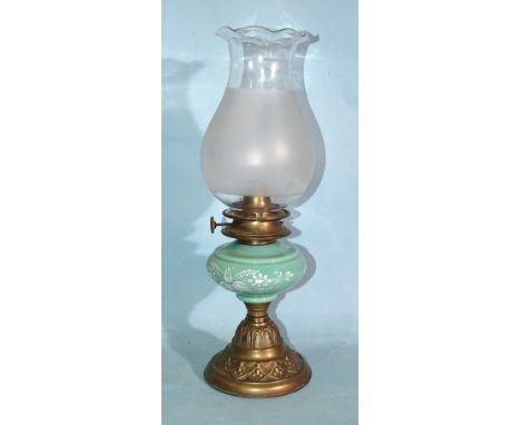 A late-19th/early-20th century oil lamp, the green opaque glass reservoir with white enamel floral decoration, on embossed de