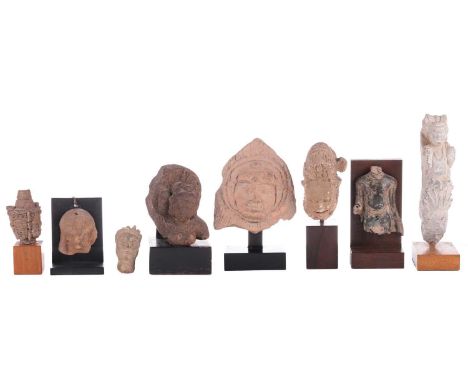 A group of Indian and other Asian stone carvings including a grey schist architectural bracket in the form of a winged Deva, 