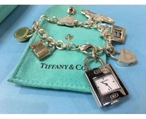 A Tiffany and Co 925 silver charm bracelet with five 925 charms and a stainless-steel padlock watch, total weight 75.6 gram, 