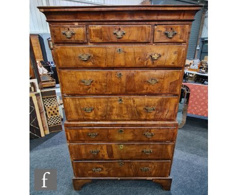 A George III cross-banded walnut chest on chest, with a cornice pediment above an arrangement of nine drawers above bracket f