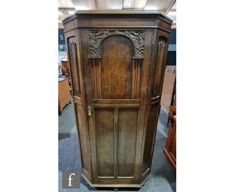 An early 20th Century oak hall robe with linen fold detail and an arched panel door, height 187cm, width 92cm and depth 47cm.