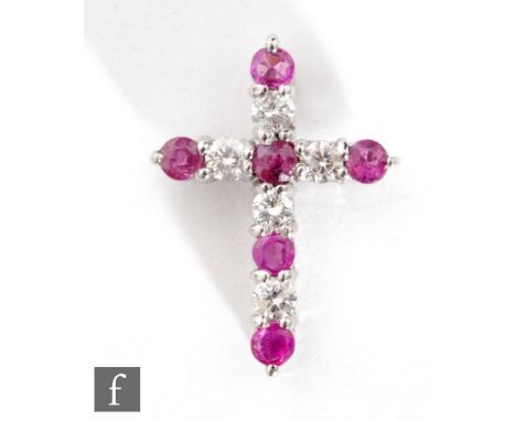 An 18ct white gold ruby and diamond cross comprising eleven alternating claw set stones, length 2.5cm. 