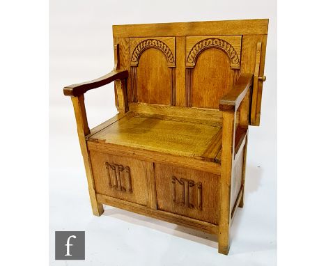 A 20th Century oak monks bench, the fold-over top with twin arched panels over the lift up seat and a linen-fold panel base, 