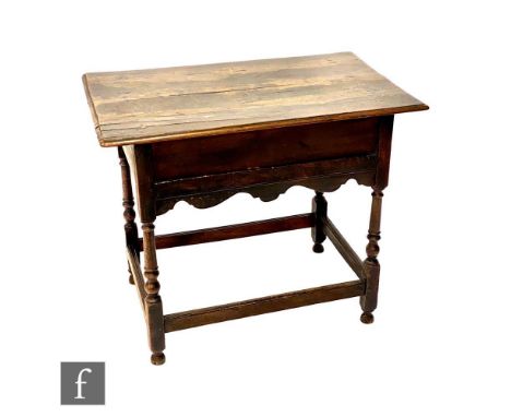 A small 18th Century oak side table lacking drawer and the space enclosed by a panel over a shaped apron, on turned legs unit