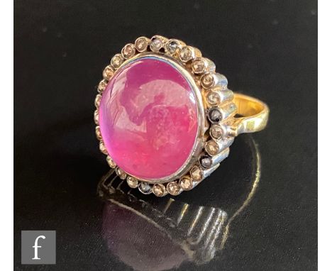 An 18ct hallmarked ruby and diamond cluster ring, central cabachon cut ruby within an old cut diamond border, all to a ribbed