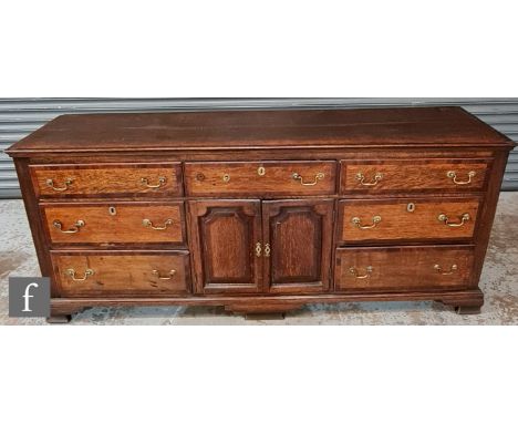 An 18th Century and later Lancashire oak dresser base, with mahogany cross-banded borders, fitted with an arrangement of seve