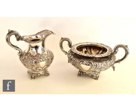 A Victorian matched hallmarked silver cream jug and sugar basin, each raised on four scroll feet and with embossed foliage de